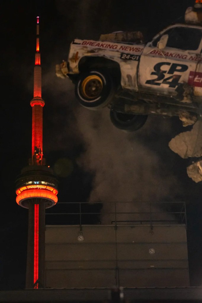 CN Tower lit red at night in the background and CP24 truck in focus