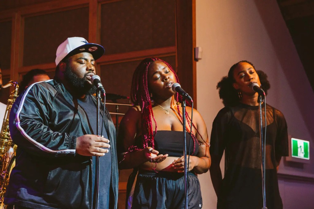 Three background vocalists singing with their eyes closed