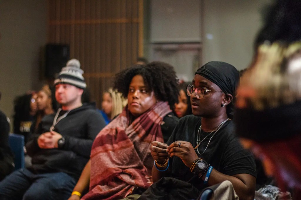 two men and one woman sitting in the front row of the RISE event with their winter hats and scarves