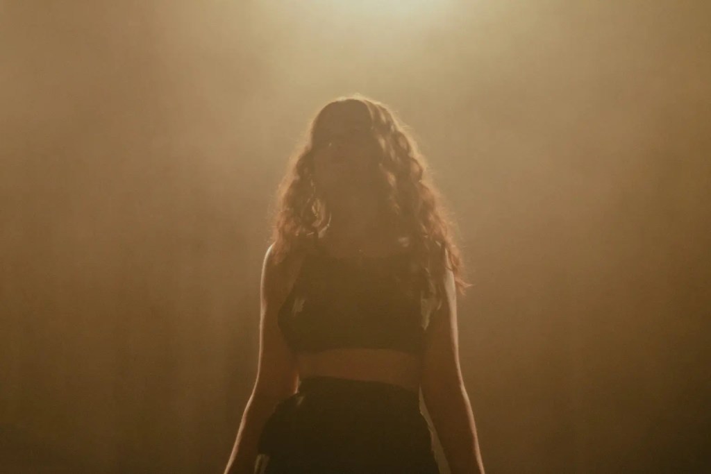 Sabrina Claudio standing on stage with a golden haze around her