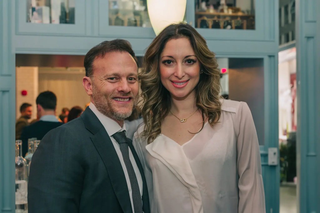 Man and woman in business attire pose together and smile for picture
