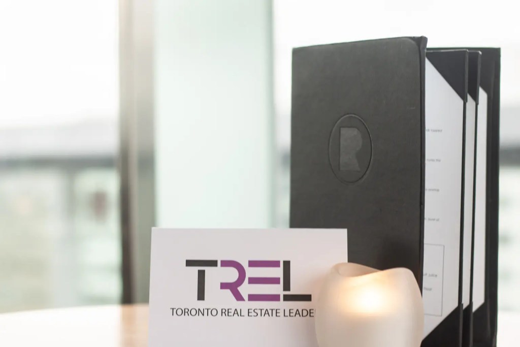 TREL name card on a table with a black menu standing upright behind it and a lit candle in front