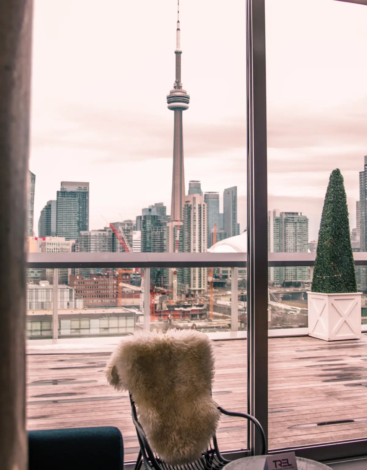 A chair with plush throw overlooking the Toronto CN Tower from a rooftop bar